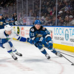Hockey Players next to advertising on dasher boards